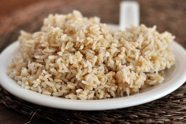 A white plate piled high with cooked brown rice.