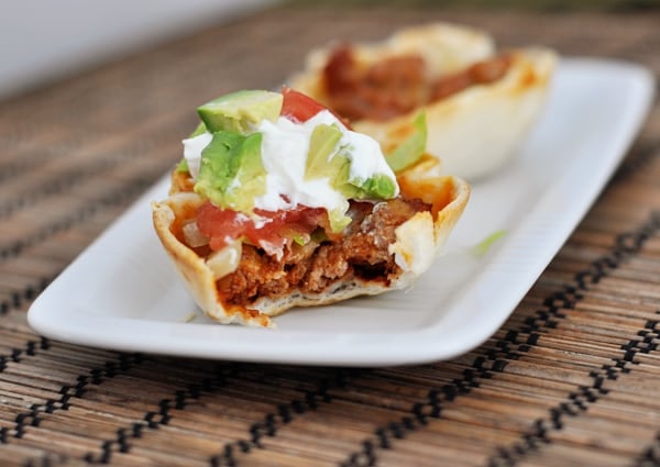 A mini taco cup with a bite taken on a white platter.