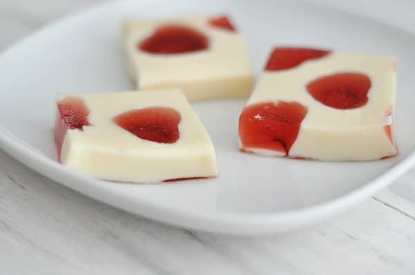 Three Jello squares with mosaic Jello red hearts embedded inside on a white plate.
