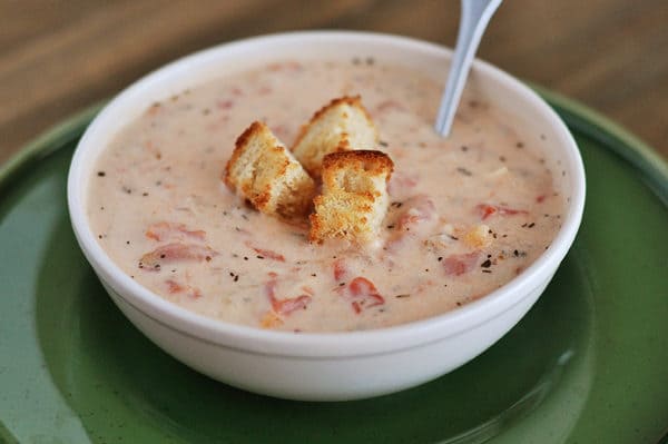 White bowl of tomato basil soup with a few croutons on top.