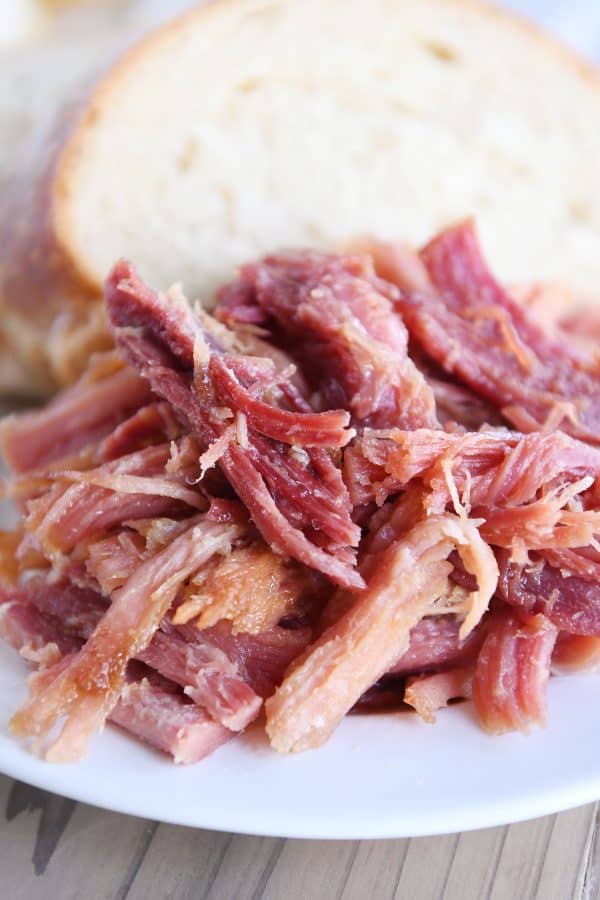 Close up of sweet baked ham on white plate with bread.