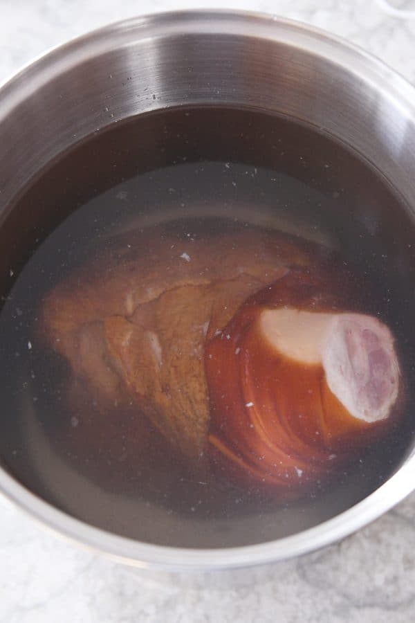 Bone-in ham in pot with vinegar and water.