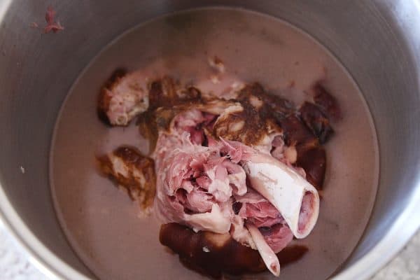 Cooked ham falling apart tender in large pot.