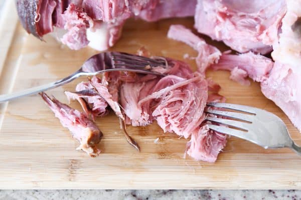 Shredding sweet baked ham with two forks.