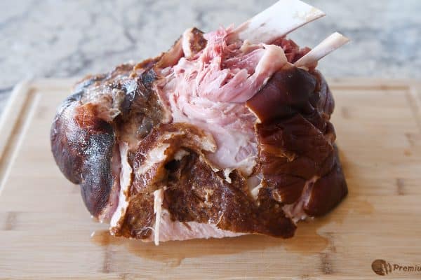 Cooked ham falling apart tender on cutting board.