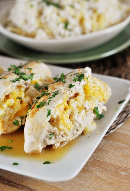 White platter with apple-stuffed chicken breasts topped with fresh parsley.