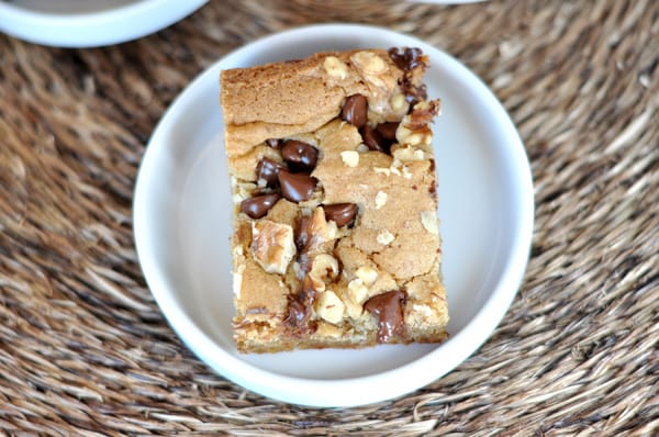 Top view of a walnut chocolate chip blondie square on a white plate.