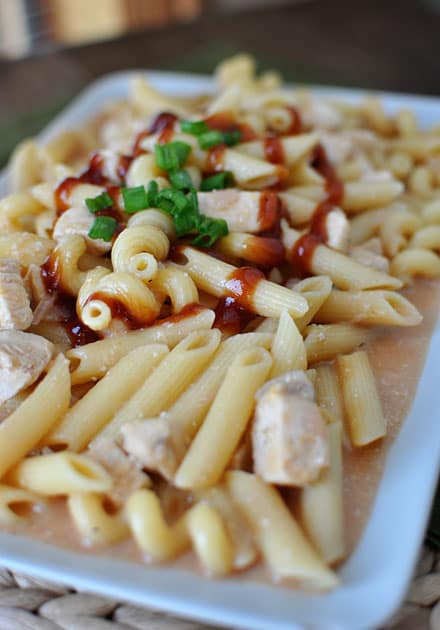 Tube pasta with pieces of chicken and BBQ sauce on top.
