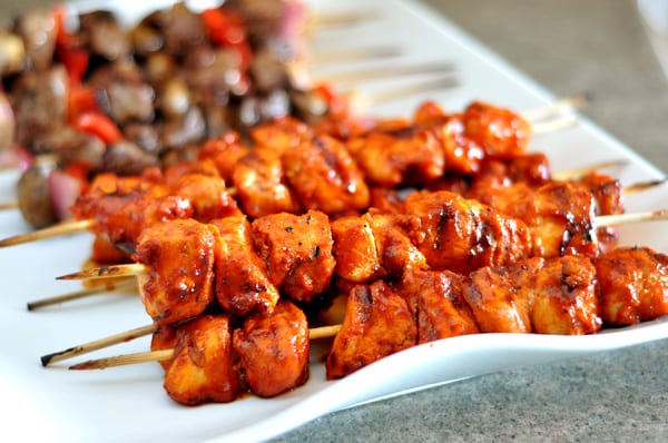 White platter filled with bbq chicken and beef and pepper kebabs.