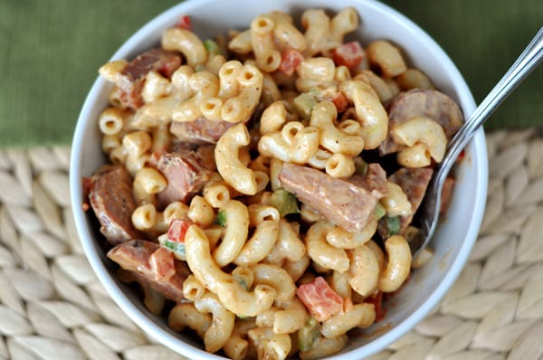 Top view of a white bowl of macaroni salad with pieces of ham and elbow noodles.