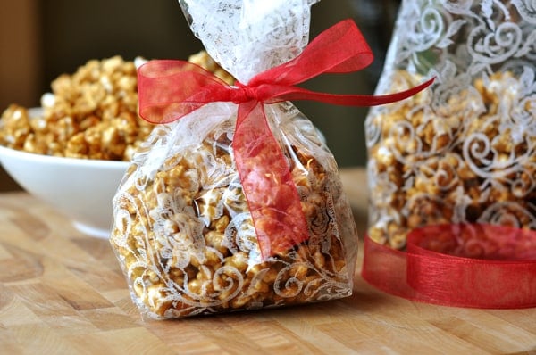 Decorative plastic bags filled with toffee popcorn and tied with a red ribbon.