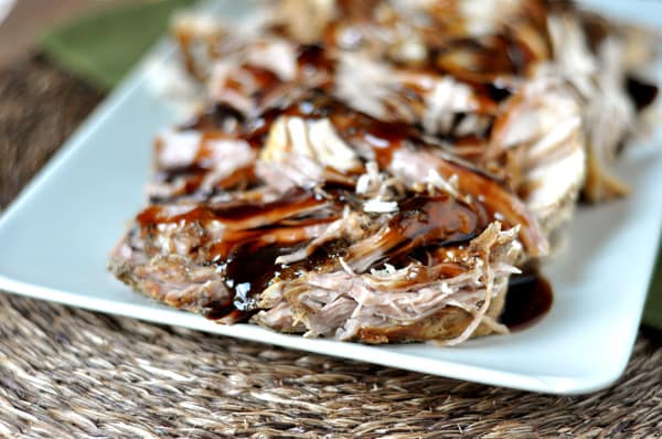 A plate full of shredded pork with balsamic glaze drizzled over the top.