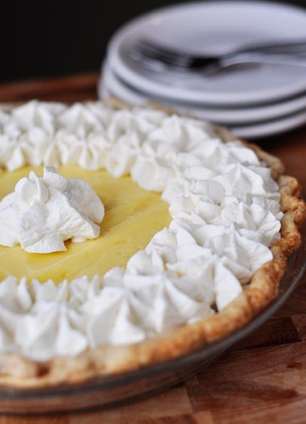 A banana cream pie with piped whipped cream frosting around the edges and in the middle of the pie.