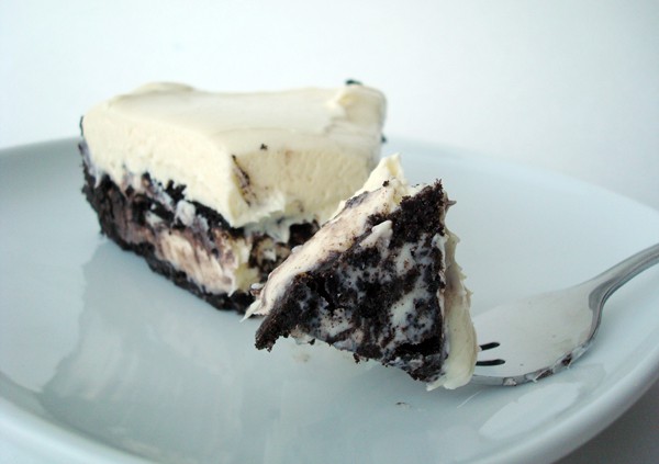 A piece of Oreo cheesecake with a bite being taken out.