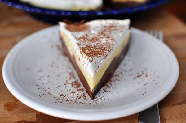 A slice of black bottom pudding pie with a sprinkled cocoa on a white plate.