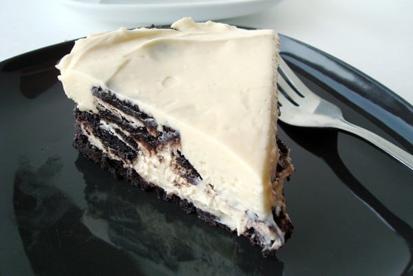 Slice of no-bake Oreo cheesecake on a black plate.