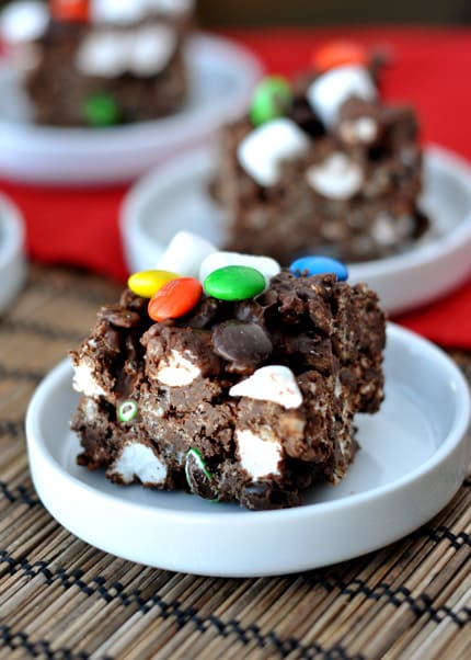 Chocolate rice krispie treat with marshmallows and M&M's on a white plate.