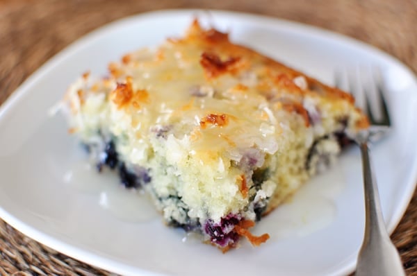 A top view of a slice of blueberry coconut cake on a white plate.
