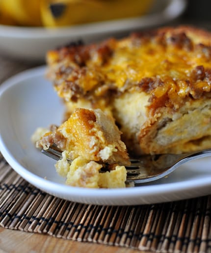 White plate with a piece of sausage and egg breakfast bake and a fork taking a bite out.