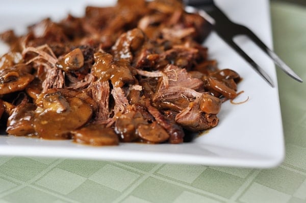 Shredded braised brisket on a white platter.