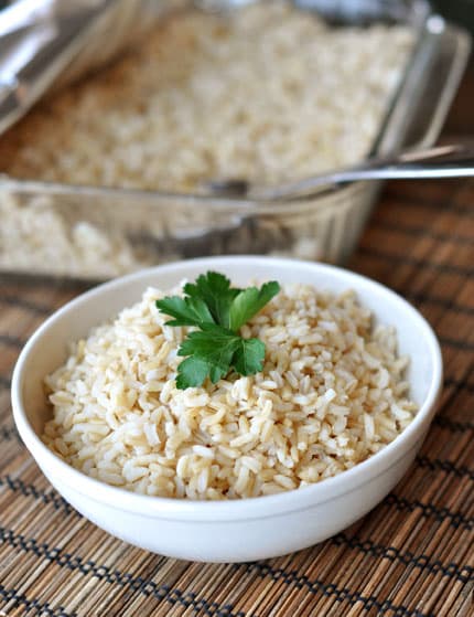 White bowl with baked brown rice and topped with parsley.