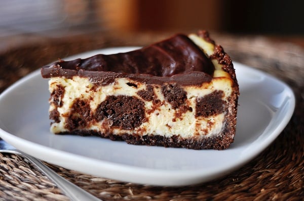 A brownie-studded slice of cheesecake on a white plate.