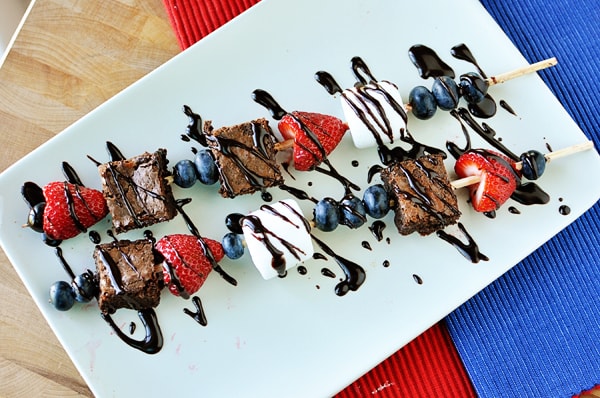 white platter with two 4th of July brownie and fruit kebabs drizzled with chocolate sauce