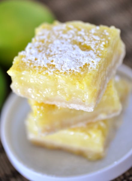 a stack of powdered sugar dusted lime shortbread bars on a white plate