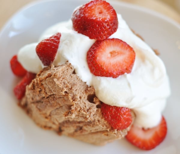 Large slice of angel food cake topped with whipped cream and sliced strawberries.