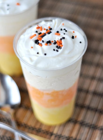 Top view of a milkshake with layers to look like a candy corn and orange and brown sprinkles on top.