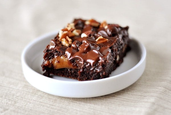 A caramel and nut-topped brownie on a round white ramekin dish.