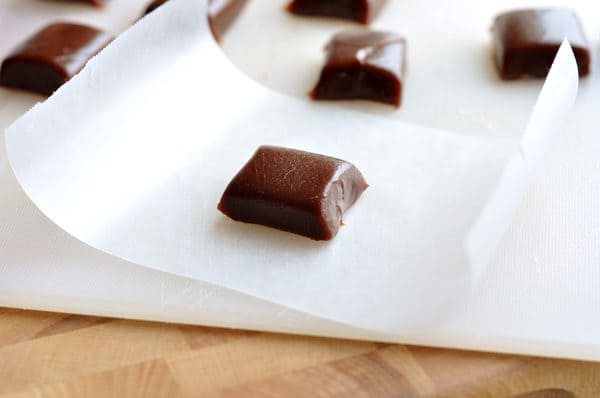 Squares of chocolate caramel on small sheets or parchment paper.