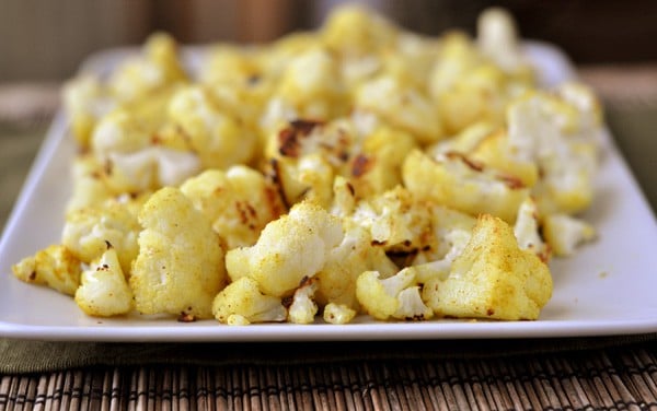 A side view of a white platter with cooked cauliflower florets.