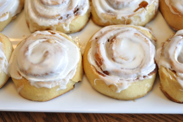 Top view of small frosted cinnamon rolls on a white platter.