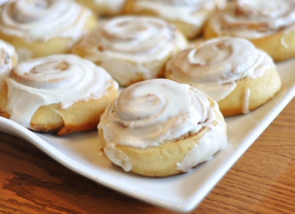 White platter with small frosted cinnamon rolls.