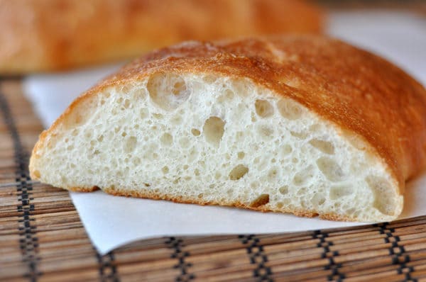 A loaf of ciabatta bread sliced open on a white napkin.