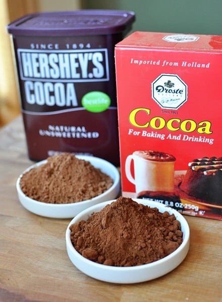 two containers of baking cocoa with a sample of each in white bowls in front of the containers