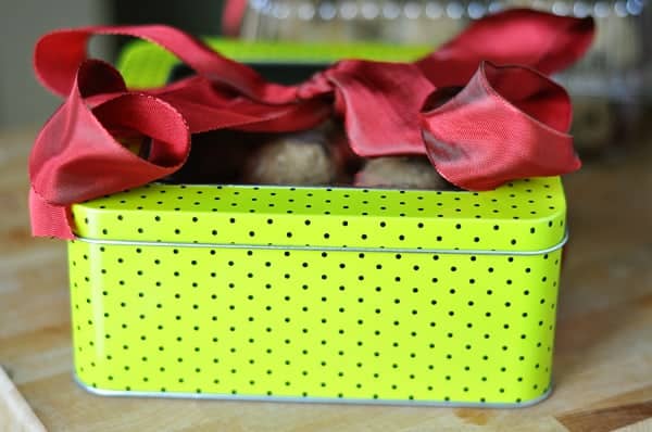 a neon green and black polka dot tin tied with a red ribbon and filled with cookie dough 