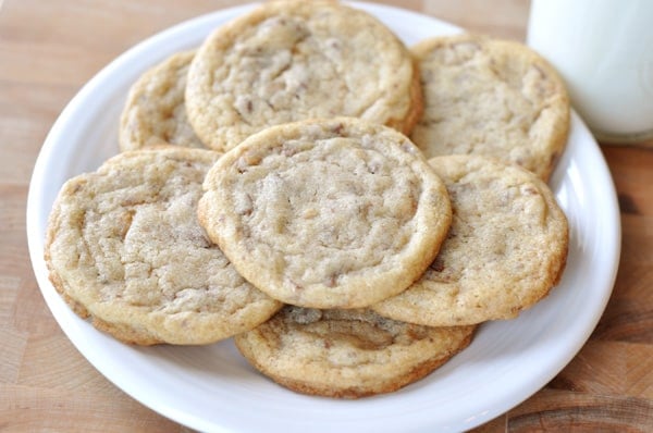 A top down view of a white plate full of toffee studded cookies.