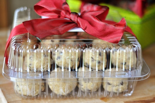 front view of a plastic container tied with a red ribbon, filled with frozen cookie dough balls