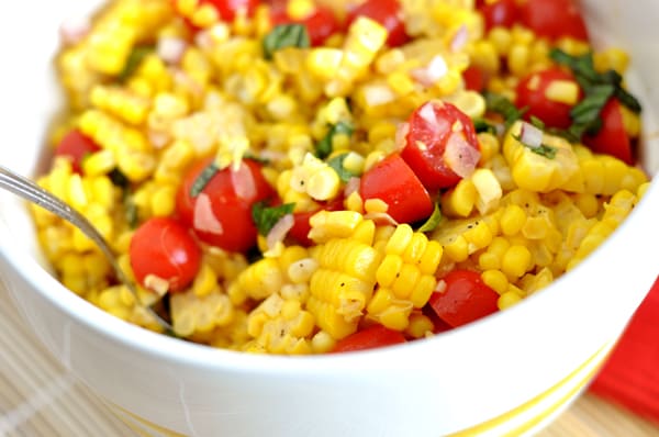 White bowl with a corn, tomato, and basil salad.