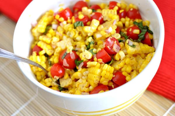 white bowl with a corn, tomato, and basil salad