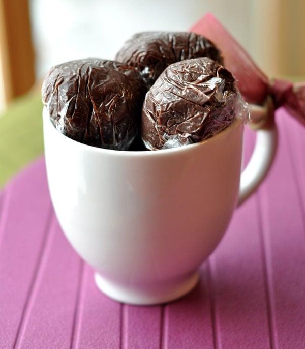 Saran wrapped hot chocolate truffle balls in a white mug.