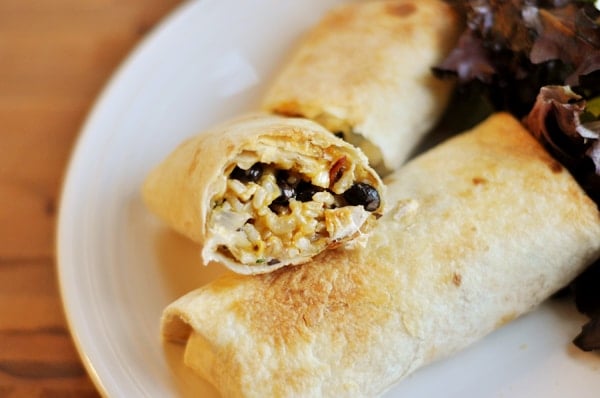 Rice and black bean chimichanga split in half on a white plate.