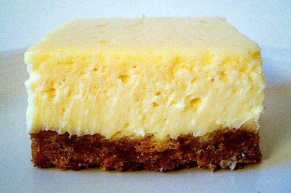 Cheesecake bar with a graham cracker crust on a white plate.