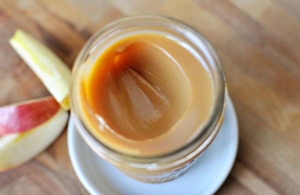 Top view of a glass mason jar of dulce de leche with one scoop taken out.