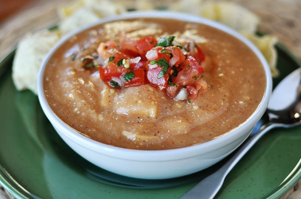 a white bowl full of chicken enchilada soup, topped with pico de gallo