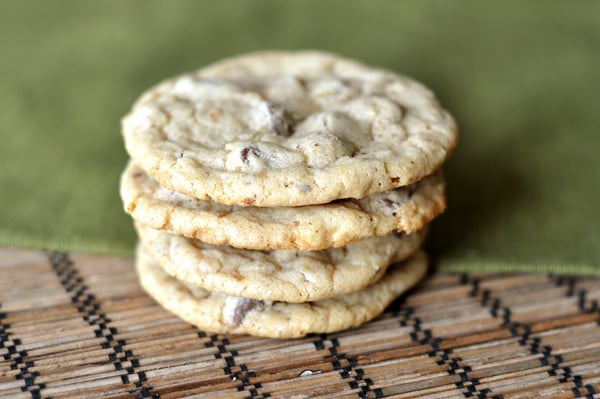 A stack of chocolate chip cookies on a mat and green napkin.