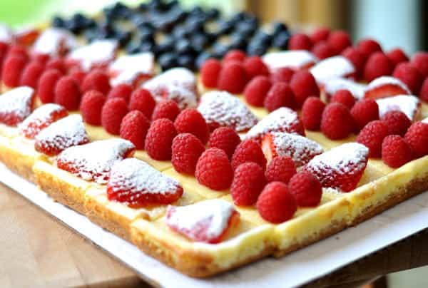 Rectangular cheesecake decorated with strawberries, raspberries, and blueberries to look like an American flag.