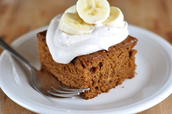 Piece of gingerbread cake topped with whipped cream and sliced bananas.